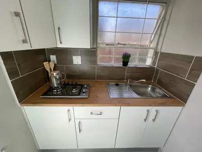 a kitchen with white cabinets and a sink and a window at Spacious stay-in bachelor apartment in Kempton Park