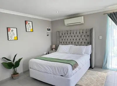 a bedroom with a white bed with a green blanket at Spacious stay-in bachelor apartment in Kempton Park