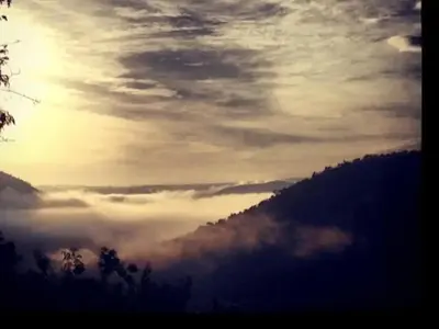 a view of a foggy mountain valley with the sun setting at Mountain Canadian Log Home in Kalkheuvel