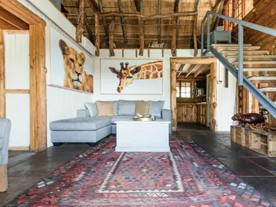 a living room with a couch and paintings of giraffes at Mountain Canadian Log Home in Kalkheuvel