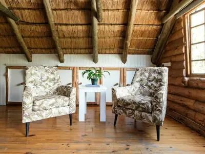 two chairs and a table in a room with wooden ceilings at Mountain Canadian Log Home in Kalkheuvel