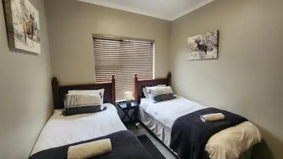two twin beds in a room with a window at Lloyds - unit 10 in Ermelo
