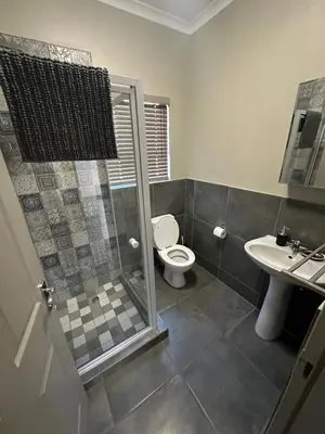 a bathroom with a shower and a toilet and a sink at Lloyds - unit 10 in Ermelo