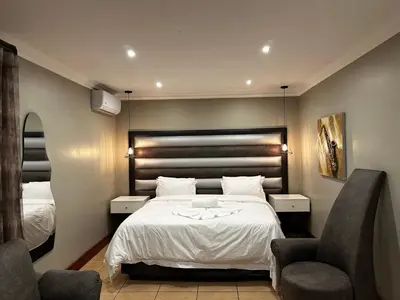 a hotel room with a bed and two chairs at Urban Villas Guest House in Pretoria