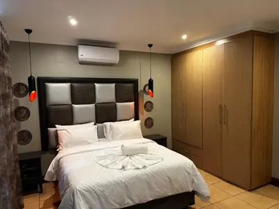 a bedroom with a white bed with a black headboard at Urban Villas Guest House in Pretoria
