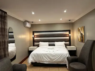 a hotel room with a bed and two chairs at Urban Villas Guest House in Pretoria