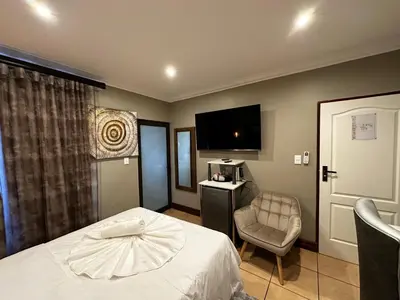 a hotel room with a bed and a chair and a television at Urban Villas Guest House in Pretoria