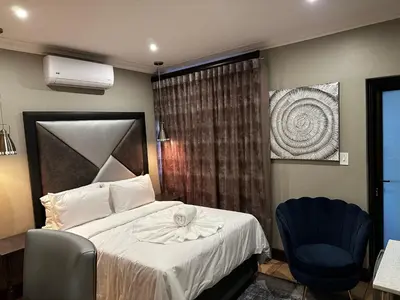 a bedroom with a bed and a blue chair at Urban Villas Guest House in Pretoria