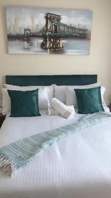 a bed with green and white pillows and a pier at Menlyn Place Staycation in Pretoria