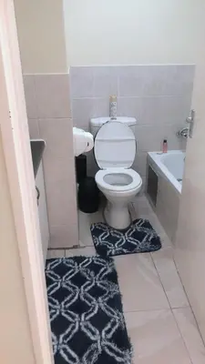 a bathroom with a toilet and a black and white rug at Menlyn Place Staycation in Pretoria