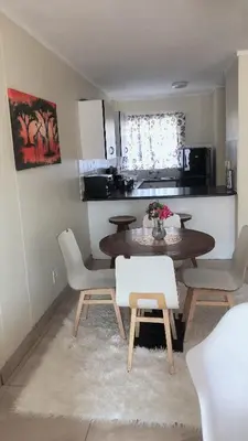 a dining room with a table and chairs and a kitchen at Menlyn Place Staycation in Pretoria