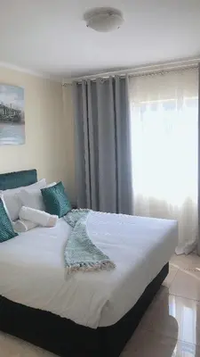 a large bed in a bedroom with a window at Menlyn Place Staycation in Pretoria
