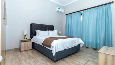 a bedroom with a large bed with blue curtains at Euphoria Golfers letting House 405 Euphoria golf and life style estate in Naboomspruit
