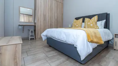 a bedroom with a large bed with yellow pillows at Euphoria Golfers letting House 405 Euphoria golf and life style estate in Naboomspruit