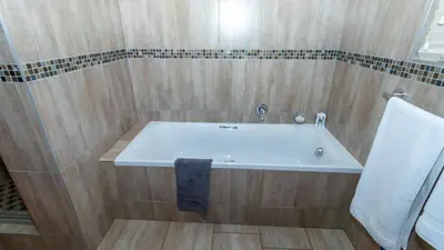 a bathroom with a bath tub with a towel at Euphoria Golfers letting House 405 Euphoria golf and life style estate in Naboomspruit