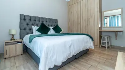 a bedroom with a large bed with a gray headboard at Euphoria Golfers letting House 405 Euphoria golf and life style estate in Naboomspruit