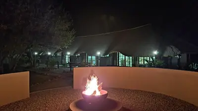 a fire pit in front of a fence at night at Hambana Lifestyle Lodge in Musina