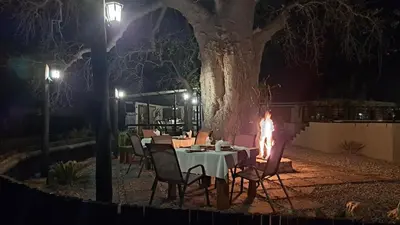 a table and chairs next to a fire place at night at Hambana Lifestyle Lodge in Musina