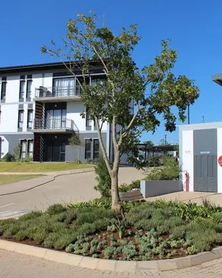 a tree in front of a white building at Lakhe Lethu Apartment: Green Valley Estate in Nelspruit