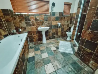 a bathroom with a tub and a sink and a toilet at Four Seasons Guesthouse - Hardekool 7 in Lephalale