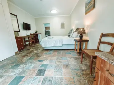 a bedroom with a bed and a table and a chair at Four Seasons Guesthouse - Hardekool 7 in Lephalale