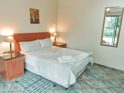 a bedroom with a bed and two lamps and a mirror at Four Seasons Guesthouse - Hardekool 7 in Lephalale