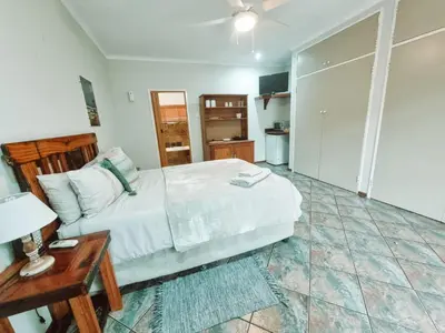 a bedroom with a bed and a table with a lamp at Four Seasons Guesthouse - Hardekool 7 in Lephalale