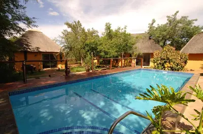 a swimming pool in front of a house at Normann Safari Bush Lodge in Phalaborwa