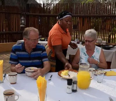 three people sitting at a table with a plate of food at Normann Safari Bush Lodge in Phalaborwa