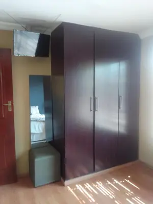 a room with a large wooden wardrobe and a stool at Room2rent Centurion in Pretoria