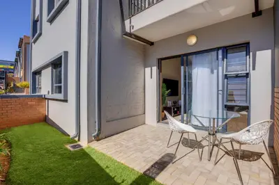 a patio with a glass table and chairs on a balcony at The Sunrise Waterfall in Midrand