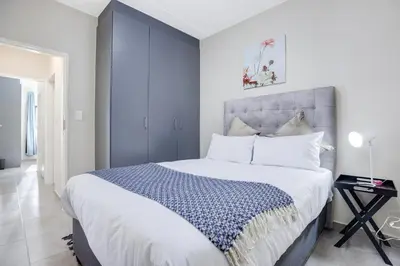 a bedroom with a large bed with a blue headboard at The Sunrise Waterfall in Midrand