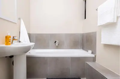 a bathroom with a white tub and a sink at The Sunrise Waterfall in Midrand