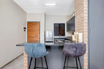a kitchen with two blue chairs at a counter at The Sunrise Waterfall in Midrand