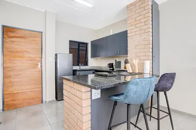 a kitchen with a counter and two bar stools at The Sunrise Waterfall in Midrand