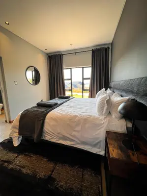 a bedroom with a large bed with a window at Highland Gate Range View in Dullstroom