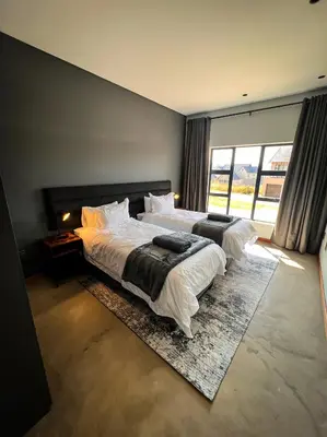 a bedroom with two beds and a large window at Highland Gate Range View in Dullstroom