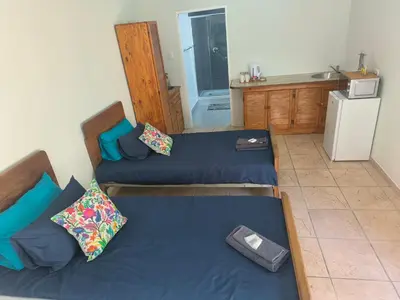 a living room with two beds and a kitchen at Sunny Stay in Groblersdal