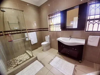 a bathroom with a shower and a sink and a toilet at REALJOY GUEST SUITES in Centurion