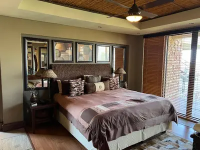 a bedroom with a large bed in a room with windows at Pumula Bush Main House in Mabula
