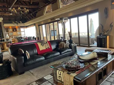a living room with a leather couch and a table at Pumula Bush Main House in Mabula