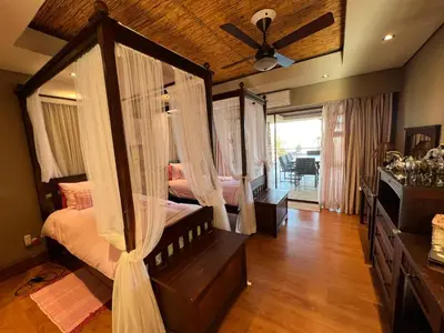 a bedroom with a canopy bed with a ceiling fan at Pumula Bush Main House in Mabula