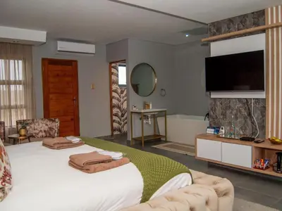 a bedroom with a large bed and a television at The Lux Hotel and Resorts in Louis Trichardt