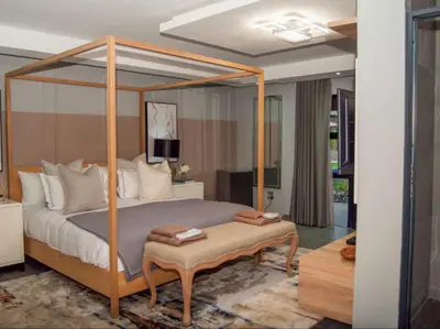 a bedroom with a canopy bed with a table at The Lux Hotel and Resorts in Louis Trichardt