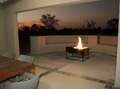 a table with a fire in the middle of a patio at Horizon Savannah in Dinokeng Game Reserve