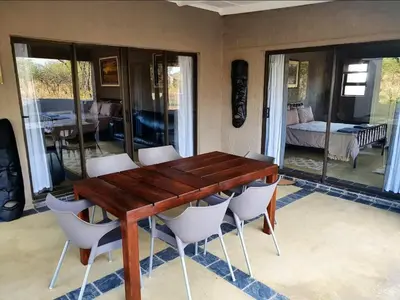a wooden table and chairs in a room with a bedroom at Horizon Savannah in Dinokeng Game Reserve
