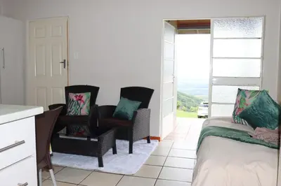 a bedroom with two chairs and a bed and a window at Panorama Chalets & Rest Camp in Graskop