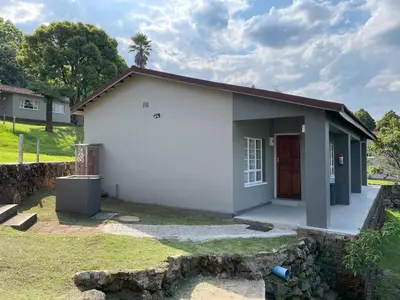 a small white house with a red door at Panorama Chalets & Rest Camp in Graskop