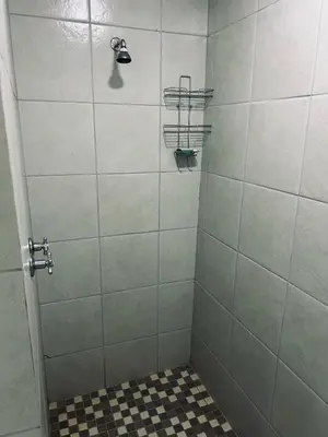 a bathroom with a shower with a black and white tile floor at The Wool House & Pablo's carolina in Carolina