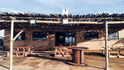 a group of picnic tables in front of a brick building at The Wool House & Pablo's carolina in Carolina